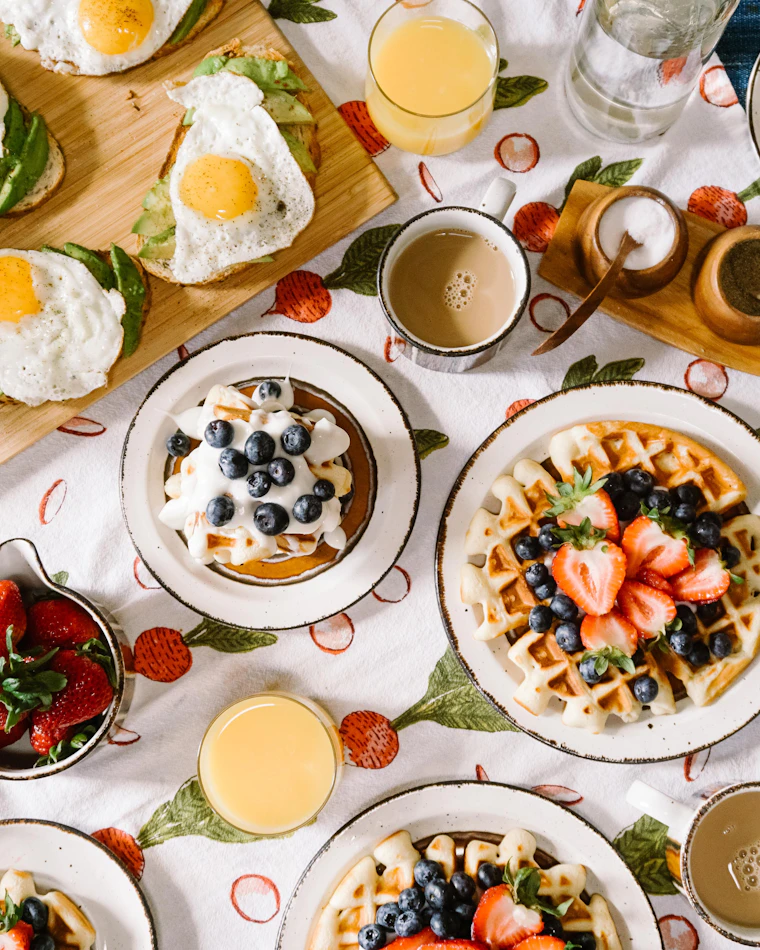 Mesa de desayuno sorpresa con waffles, huevos, jugo de naranja recién exprimido y fruta fresca servida al amanecer en Bogotá