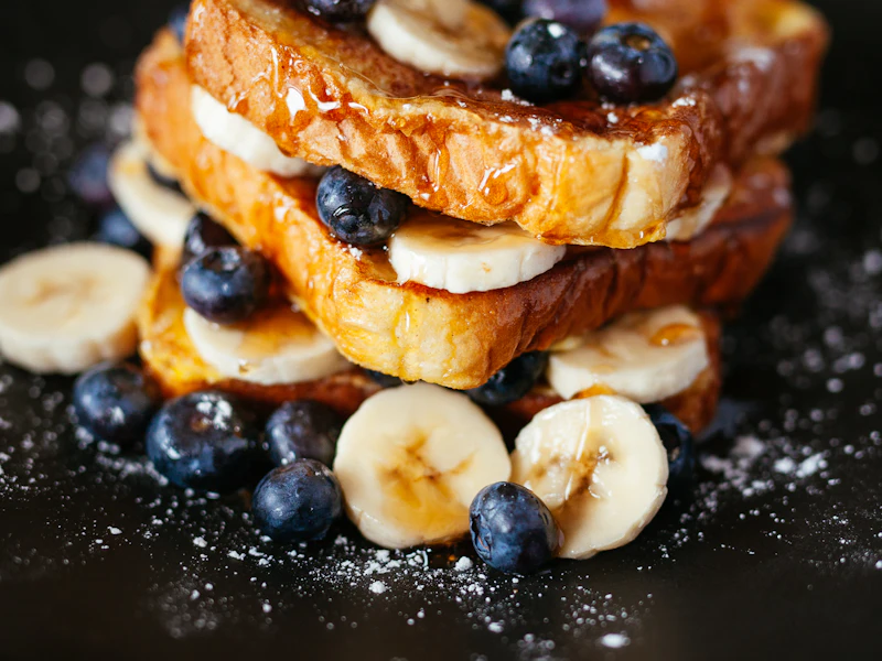 Torre de tostadas francesas con arándanos, banano y miel del desayuno de waffles en Bogotá